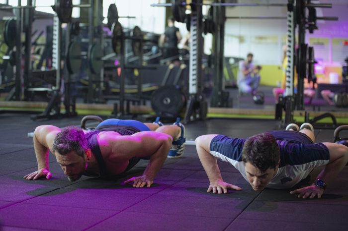 Due uomini eseguono push-up durante un allenamento funzionale in palestra presso Ego Wellness.