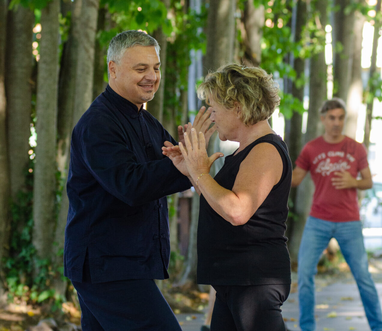 Sessione di Tai Chi all'aperto con istruttore e partecipanti concentrati nei movimenti.