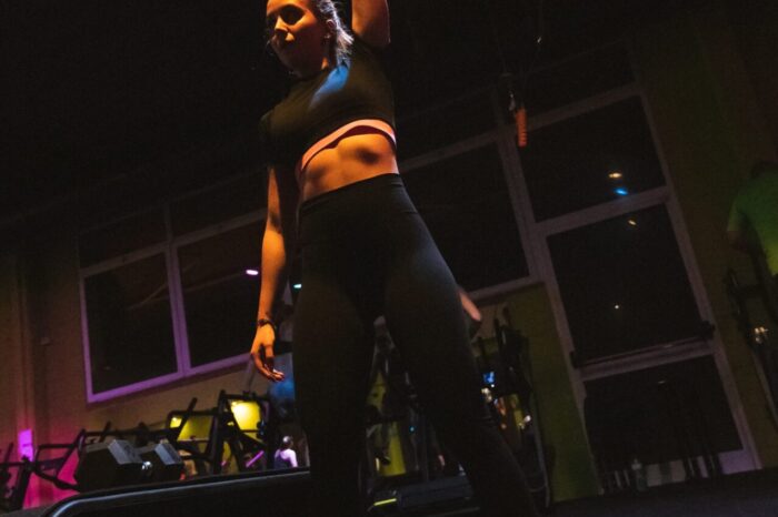 Person lifting a dumbbell overhead in a dimly lit gym at Ego Wellness Center