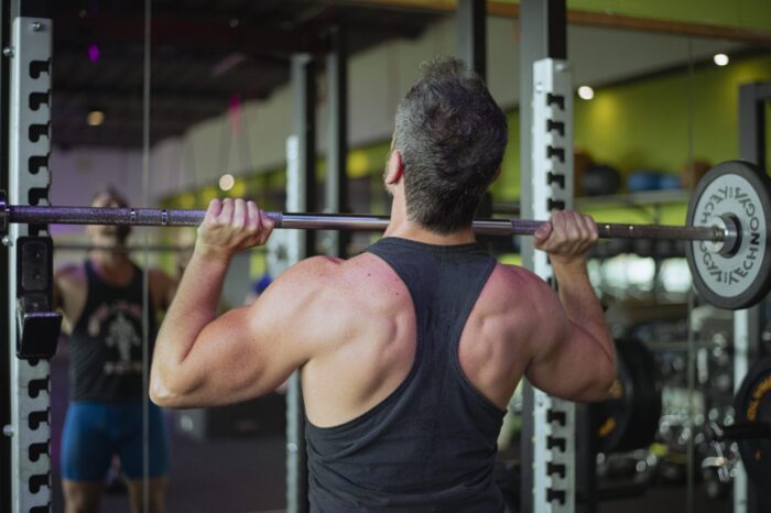 Man lifting a barbell in the gym for strength exercise at Ego Wellness